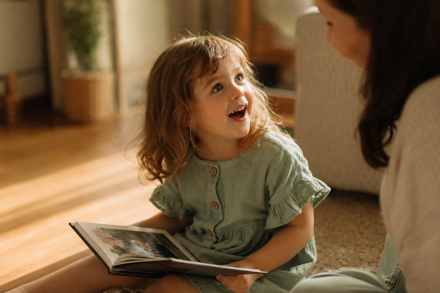 Young child sitting on the floor, delighted, holding open a hardcover photo book filled with their own memories